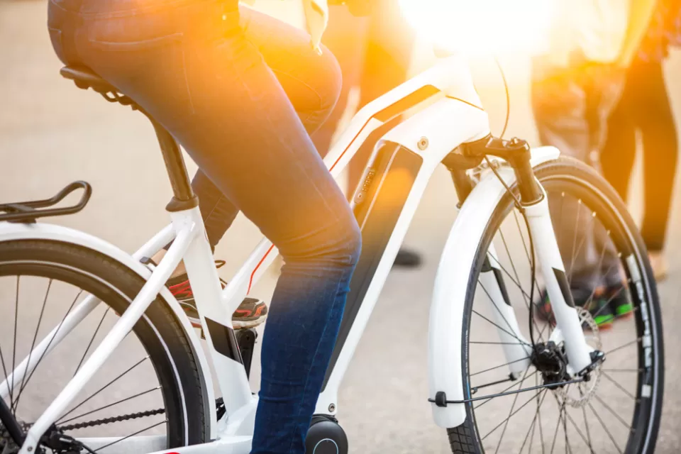 An electric bicycle is shown with the legs of a human who is riding the e-bike.